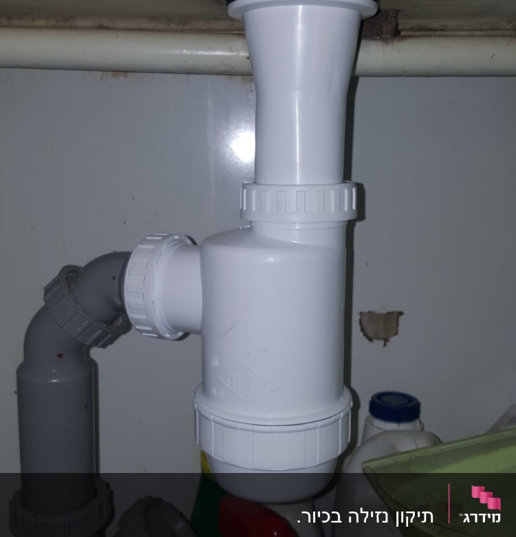 צינור פלסטיק לבן מתחת לכיור עם מחברים